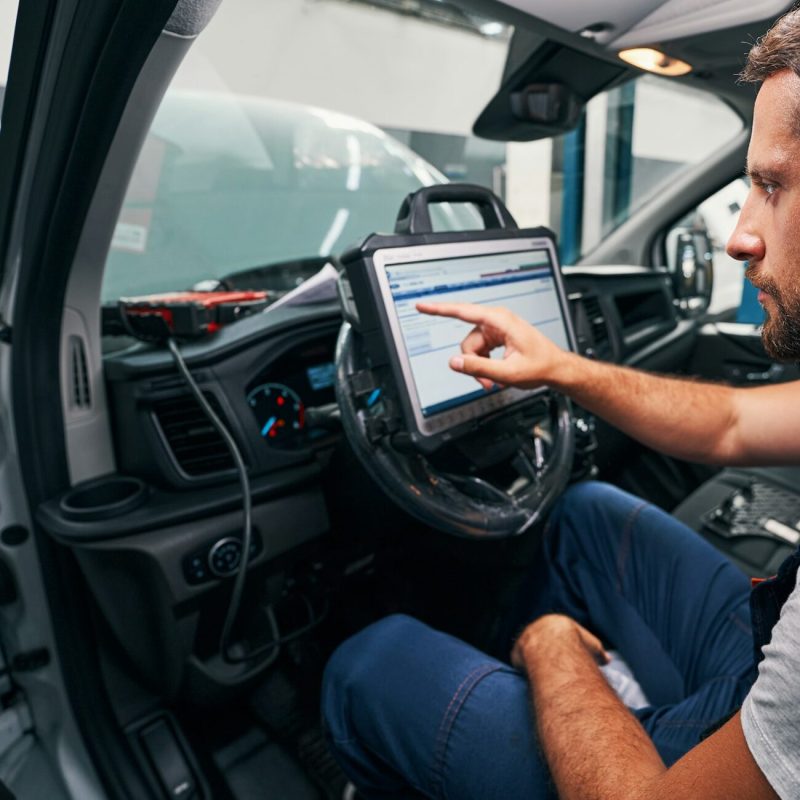 Auto mechanic providing car diagnostics in cabin