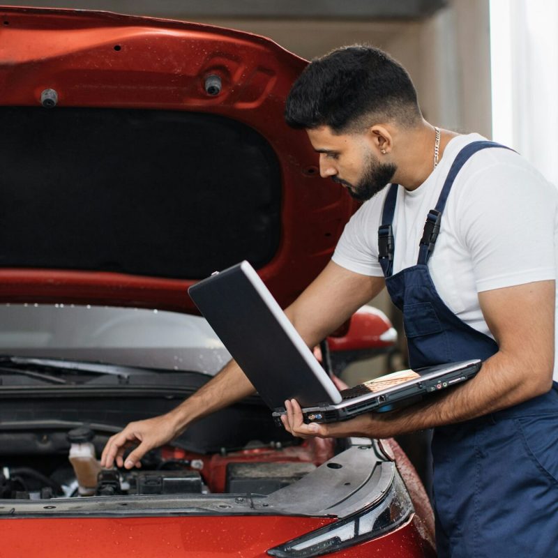 Mechanic man mechanic manager worker using a laptop computer checking car
