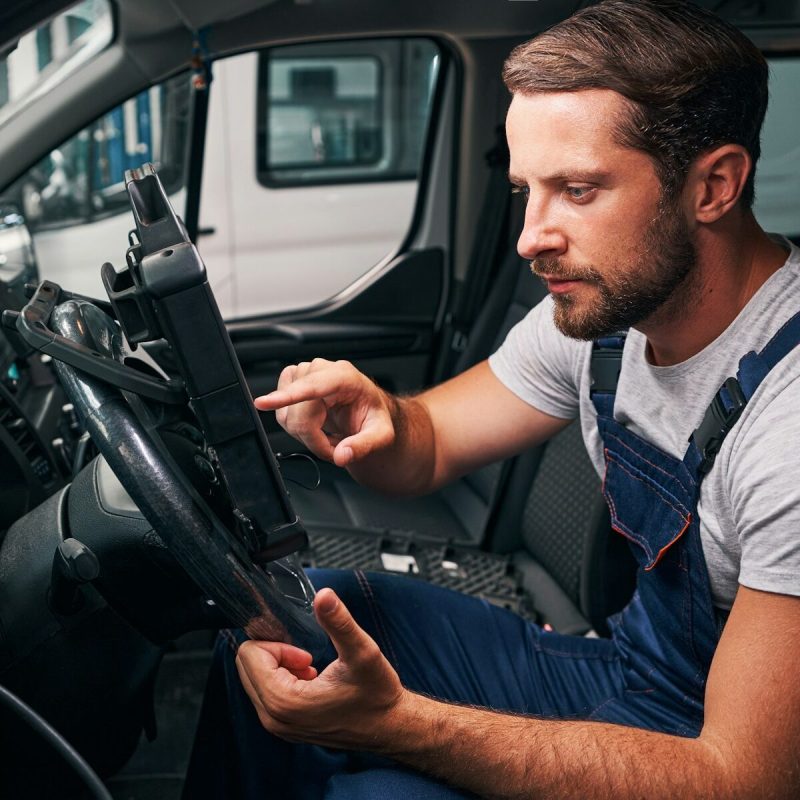 Young automotive repairman is scanning car settings
